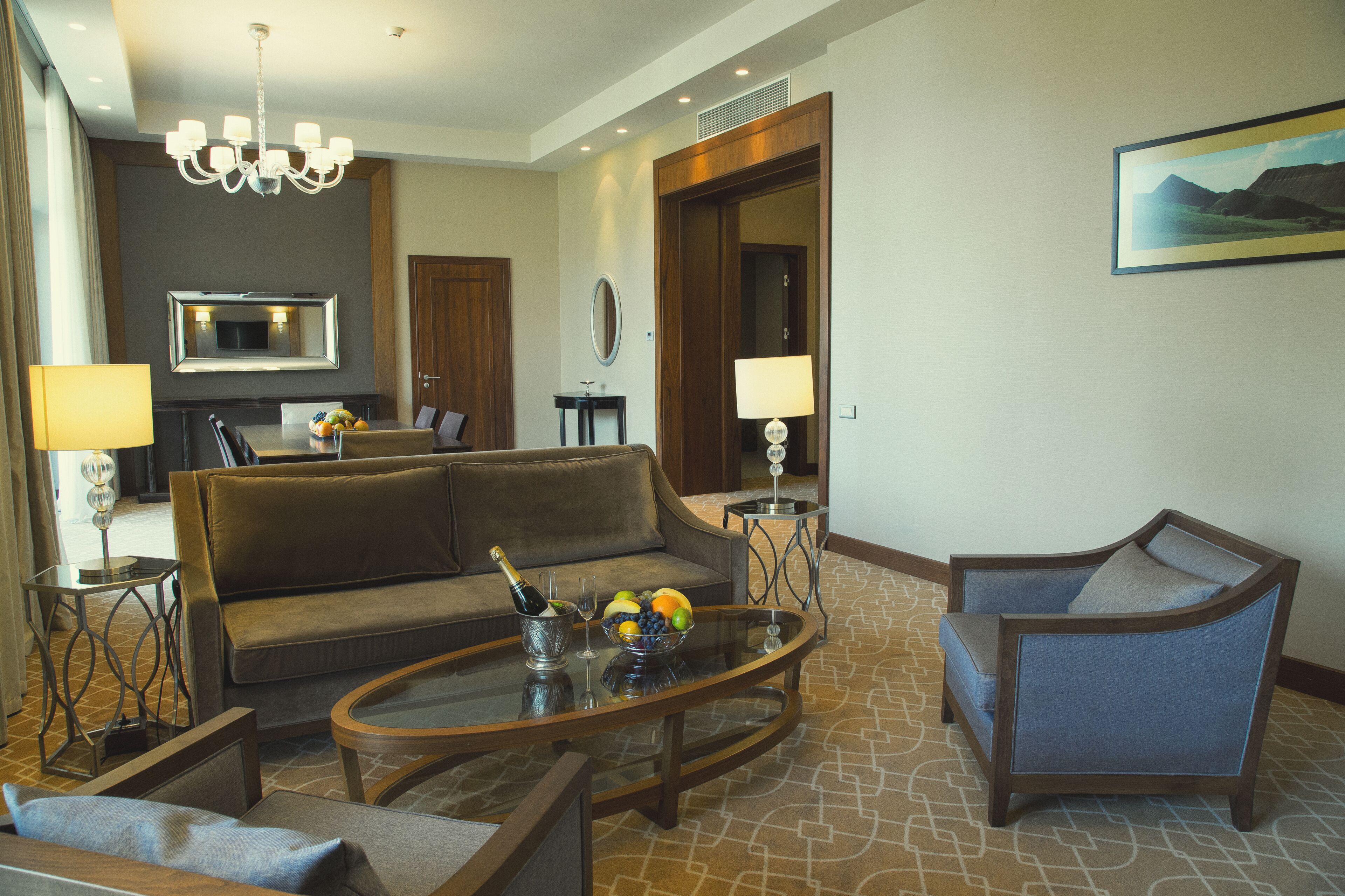 A modern living room with a sofa, armchairs, a coffee table, and a TV.
