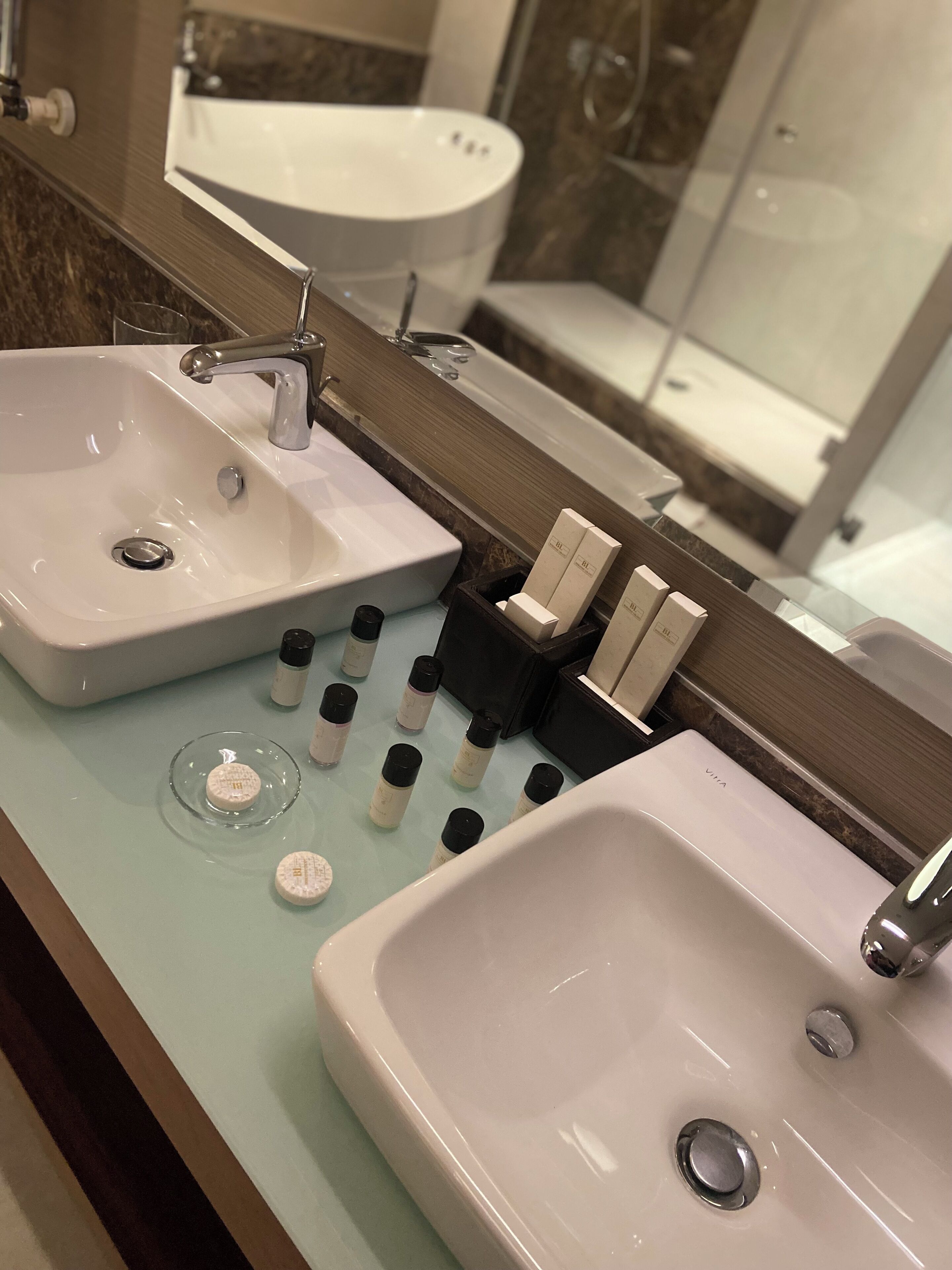 Een badkamer met twee wasbakken, een spiegel en toiletartikelen op het aanrecht.