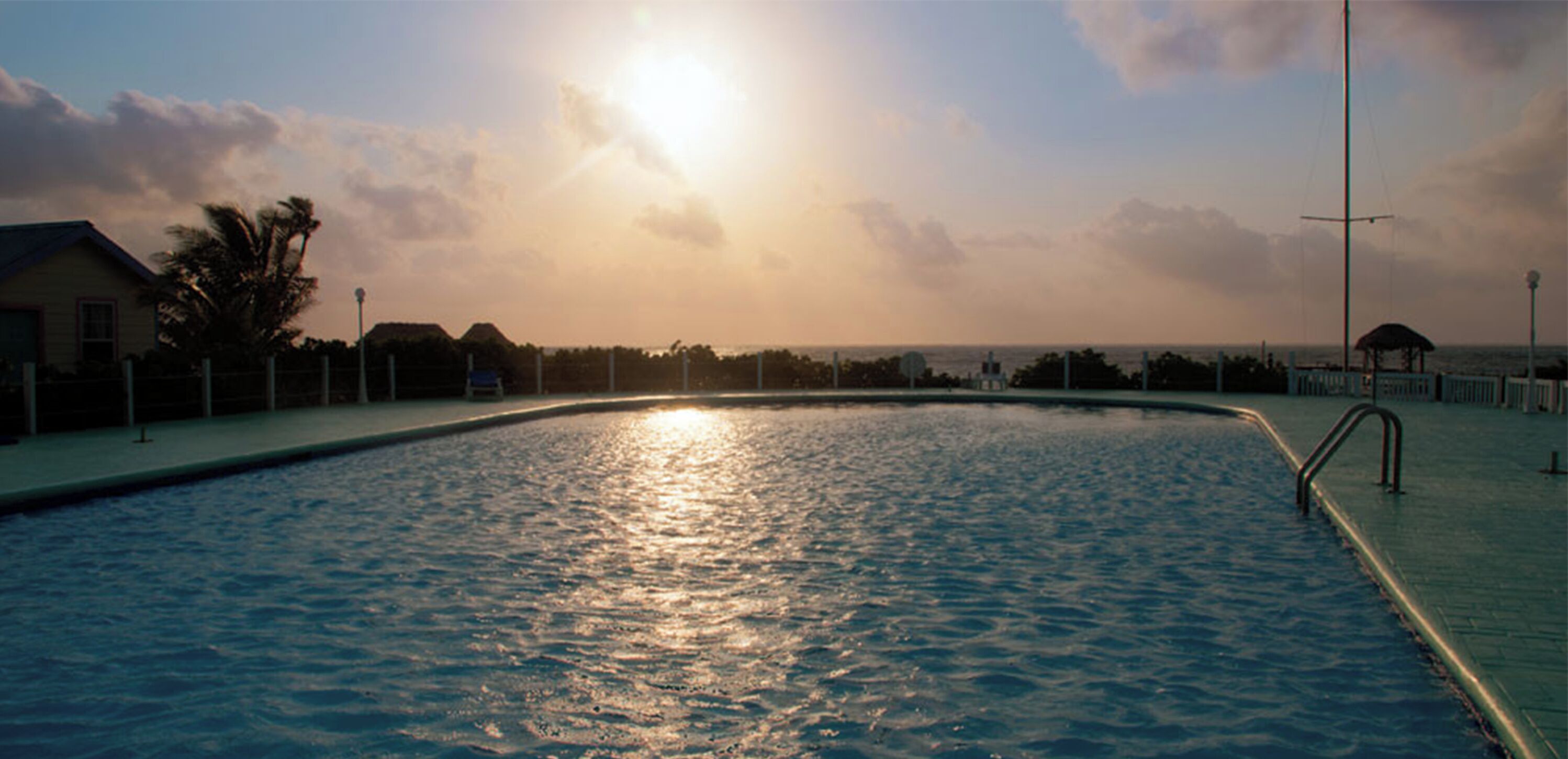 Ein Schwimmbecken mit blauem Himmel und Blick auf einen fernen Strand.