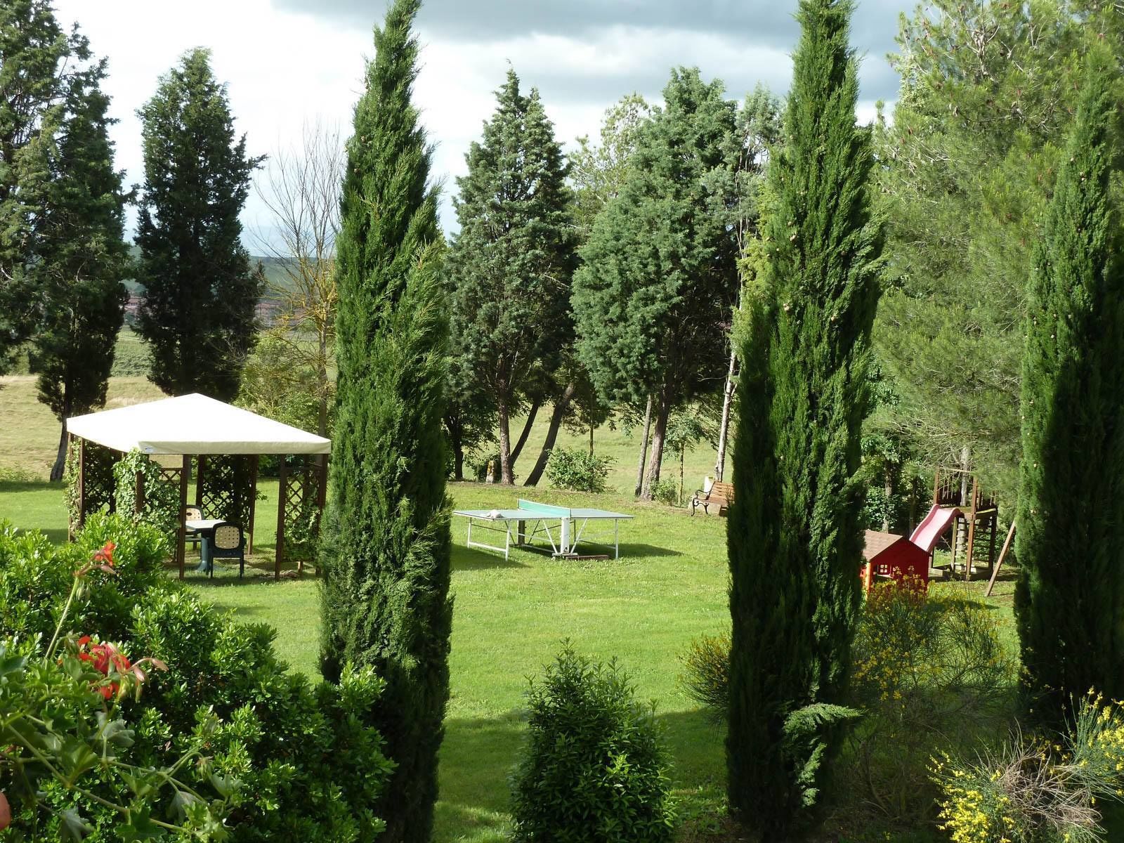A garden with a gazebo, a table tennis table, and a playground.