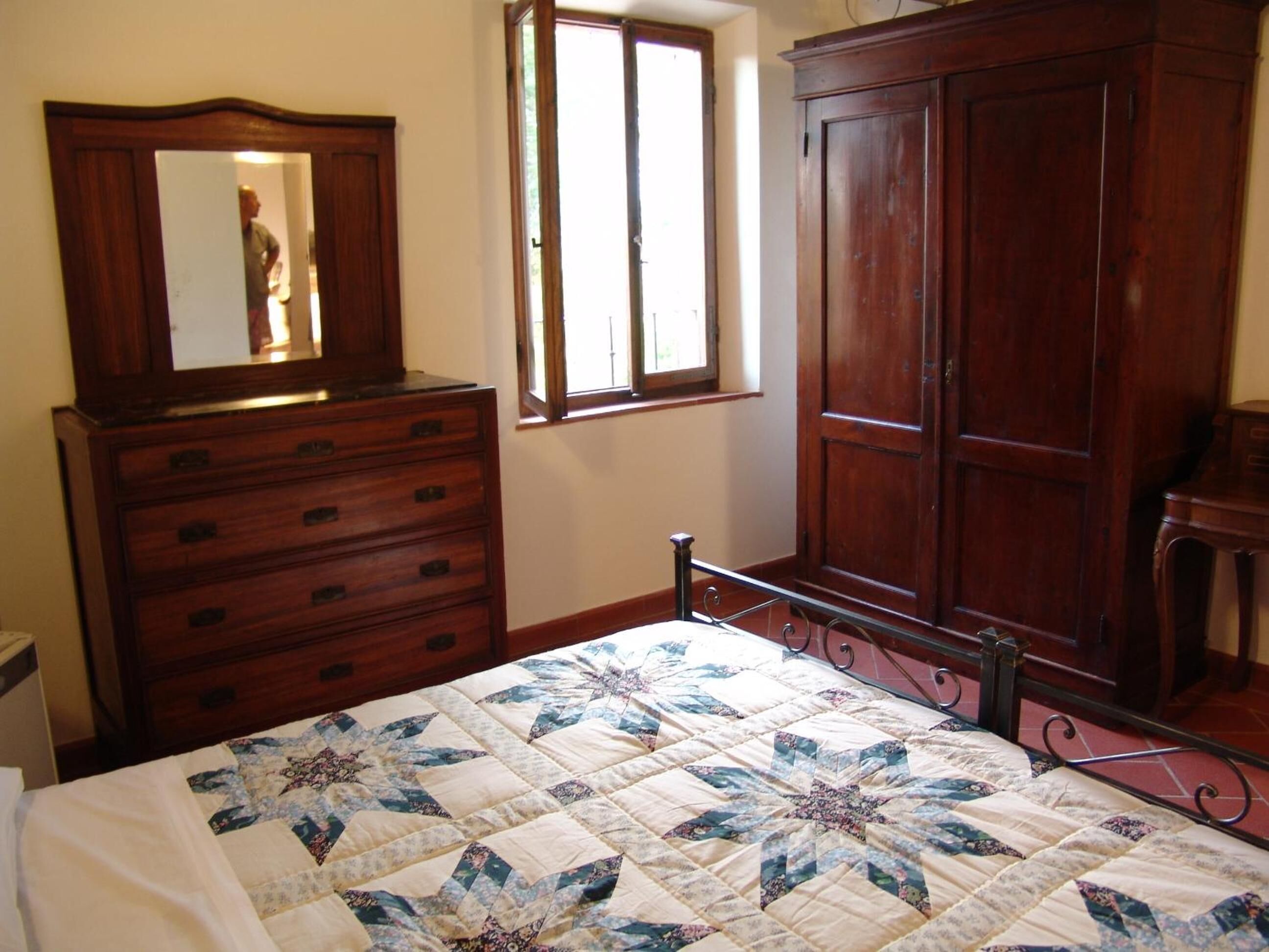 Un dormitorio con cama, cómoda, armario y ventana.