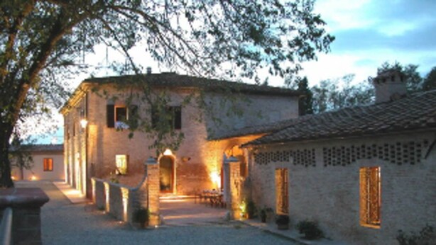 Un edificio in pietra con un cortile interno, caratterizzato da un arco centrale e un tetto in tegole.