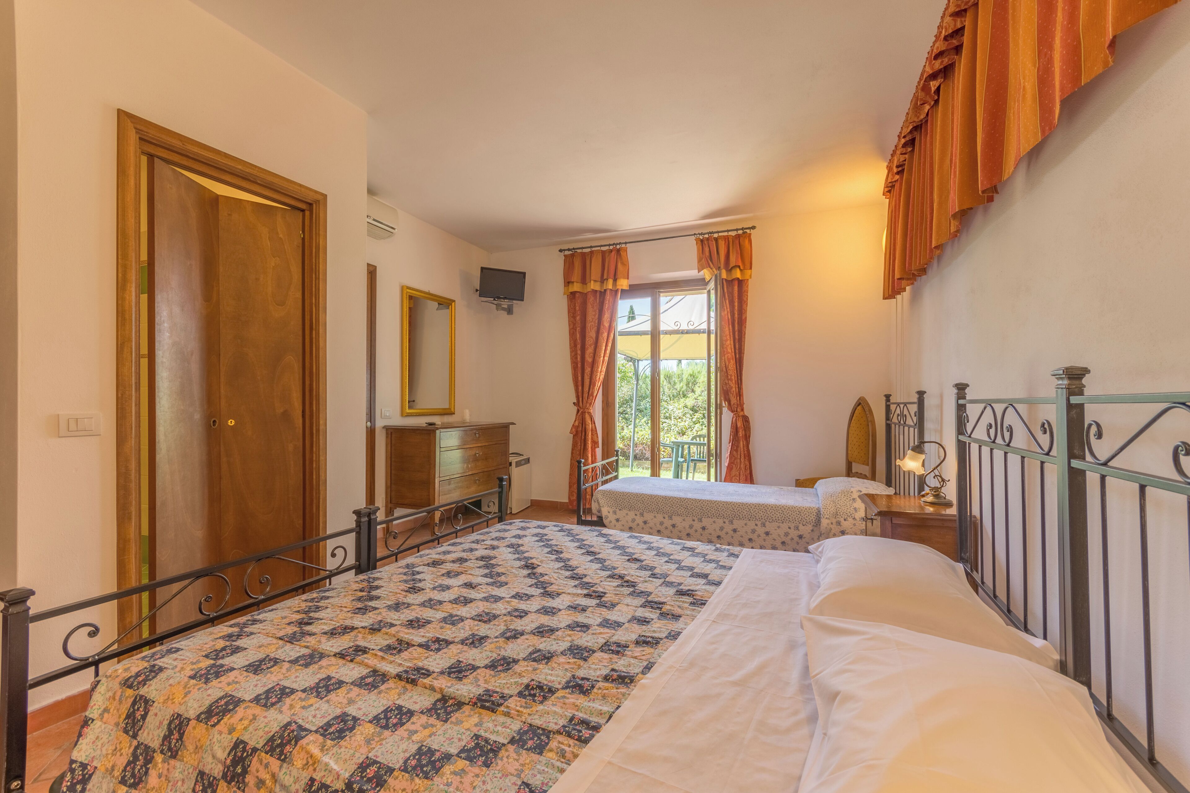 Une chambre à coucher avec un grand lit, un lit plus petit, une commode, un miroir et une fenêtre avec des rideaux.