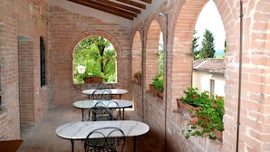 Un patio coperto con pareti in mattoni, aperture ad arco e posti a sedere all'aperto.
