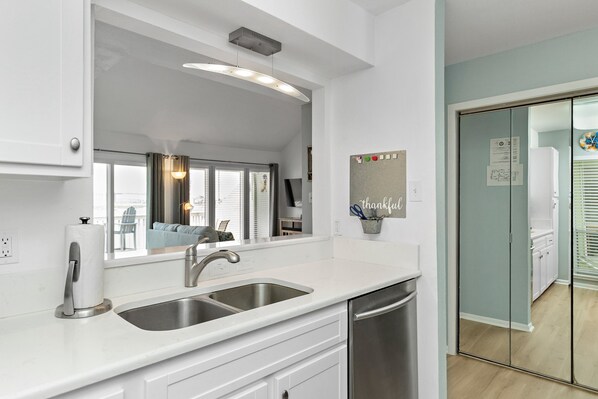 A modern kitchen with a double sink, stainless steel appliances, and a large window. - Tranquil Waterfront Escape | Stunning Sunset Views (Corpus Christi)