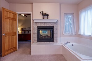 A bathroom with a fireplace, a bathtub, and a wooden door. - Mountain Views, Large Awesome Home in Gated Community  - 7 Miles from AF Acad (Colorado Springs)