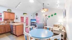 A modern kitchen with wooden cabinets, a blue dining table, and white chairs.