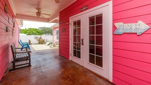 A pink house with a porch, a sign reading "Beach Bound", and a bench.