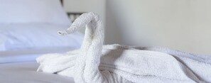 A neatly folded white bathrobe on a bed. - Eka Resorts (Sakleshpur)