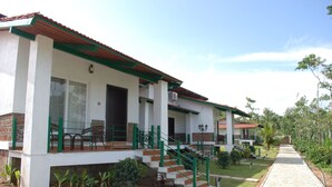 A two-story building with a red-tiled roof, a staircase with green railings, and a paved pathway leading to the entrance. - Eka Resorts (Sakleshpur)
