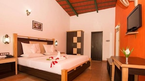 A hotel room with a bed, bedside table, lamp, wardrobe, and a television. - Eka Resorts (Sakleshpur)