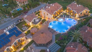 A large swimming pool surrounded by multiple buildings with outdoor seating areas and a well-lit patio. - Dalyan Live Spa Hotel (Ortaca)