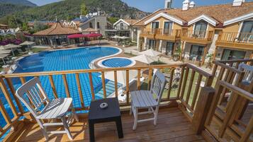 Una terraza de madera con piscina, sillas y una mesa.