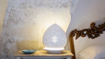 A lamp with a spherical design on a wooden nightstand next to a bed with a decorative headboard.