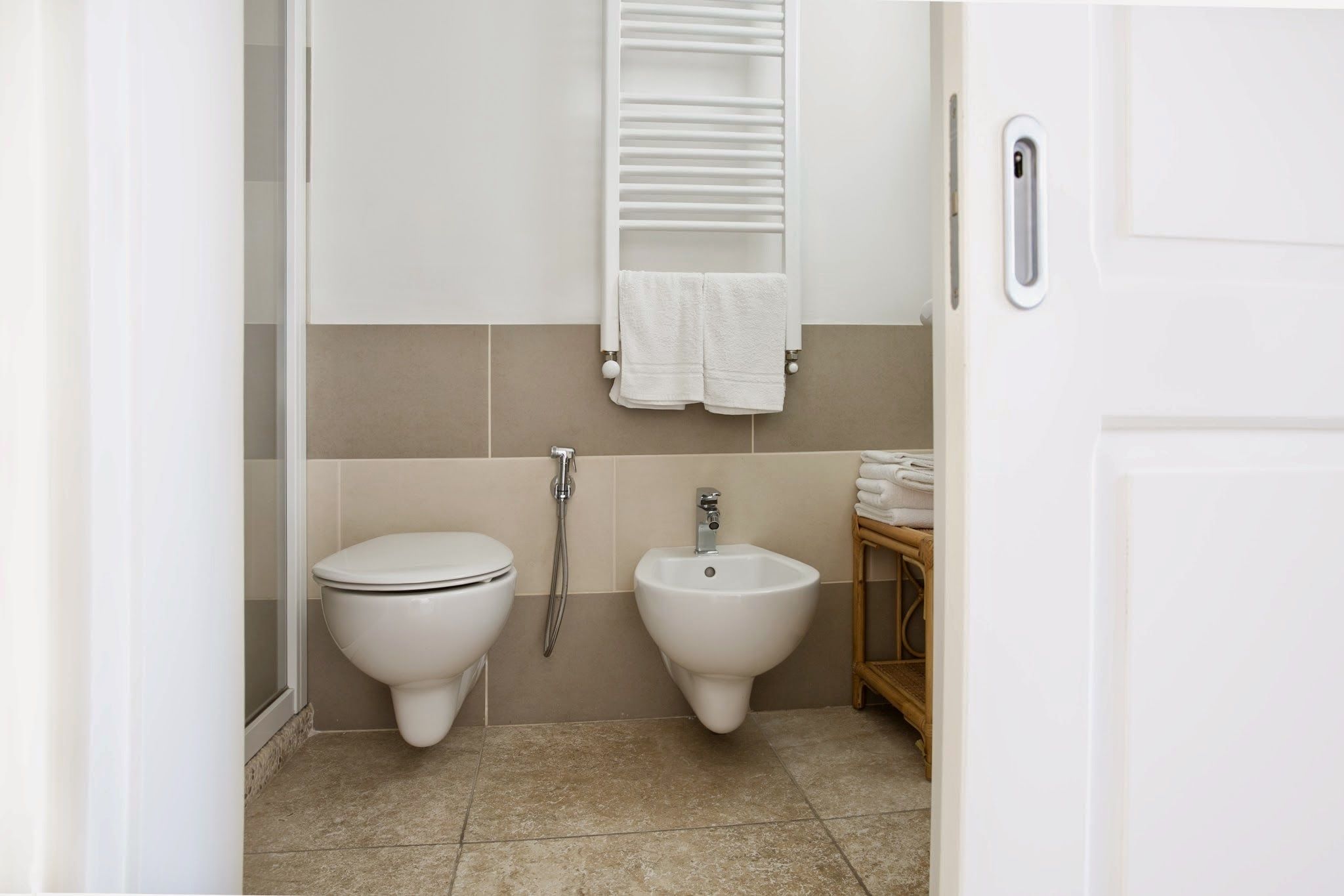 Une salle de bain équipée de toilettes, d’un bidet et d’un porte-serviettes.