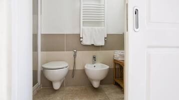 Une salle de bain équipée de toilettes, d’un bidet et d’un porte-serviettes.