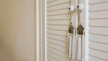 A pair of white tassel earrings hanging on a white wall with horizontal lines.