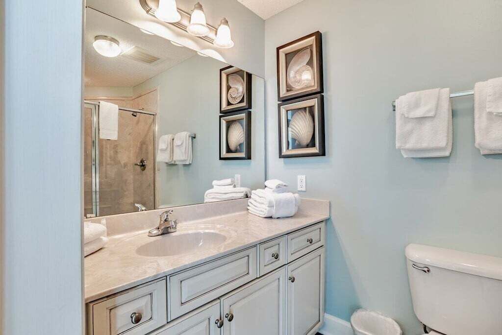 Un baño con lavamanos, espejo y cuadros en la pared.