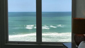 Ein Fenster mit Meerblick, eine Lampe und eine strukturierte Wand.