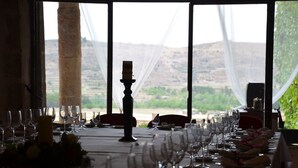 Una mesa de comedor lista para una comida, con copas de vino y una vela, con vistas a un paisaje montañoso.
