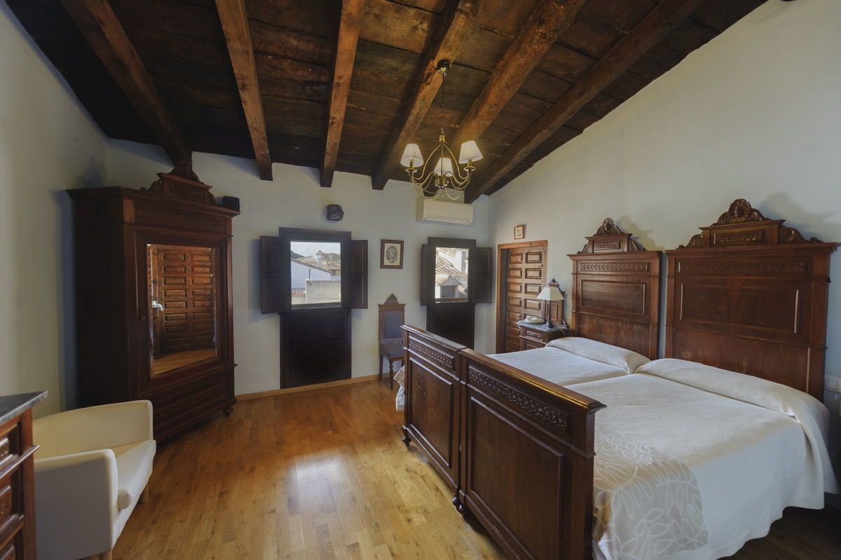 Un dormitorio con muebles de madera, un candelabro y vistas por la ventana.