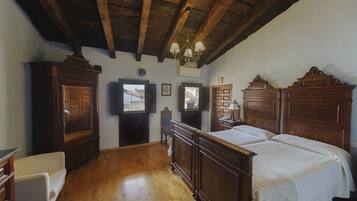 Un dormitorio con muebles de madera, un candelabro y vistas por la ventana.