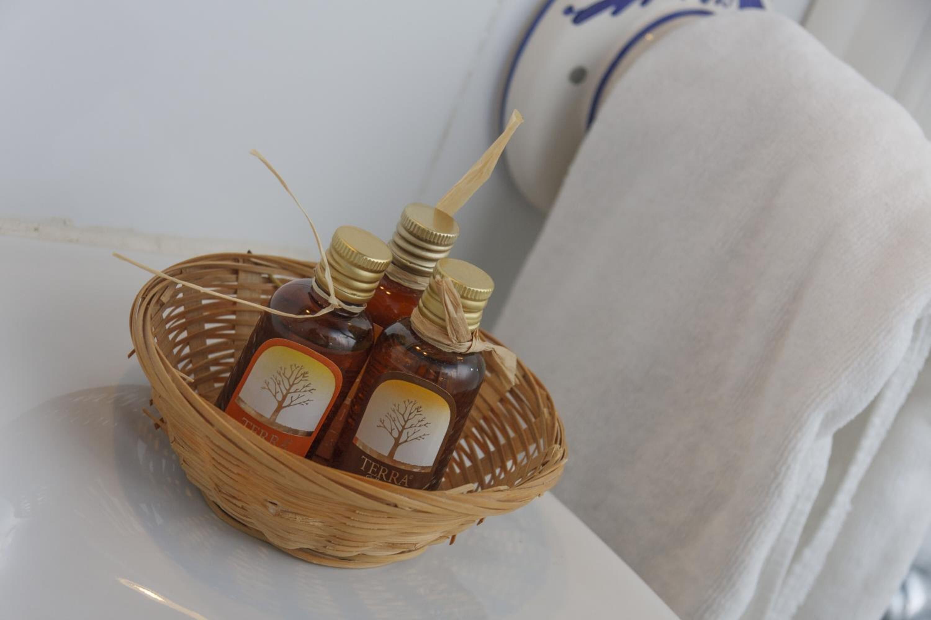 Una cesta de mimbre con tres botellas etiquetadas, sobre una superficie blanca.