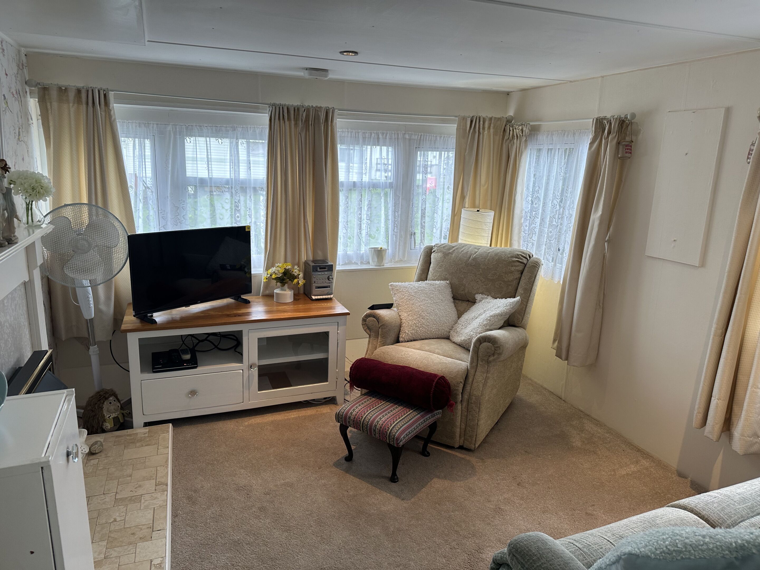 A living room with a TV, a fan, a chair, and a sofa.