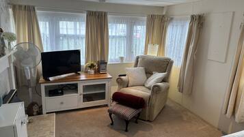 A living room with a TV, a fan, a chair, and a sofa.