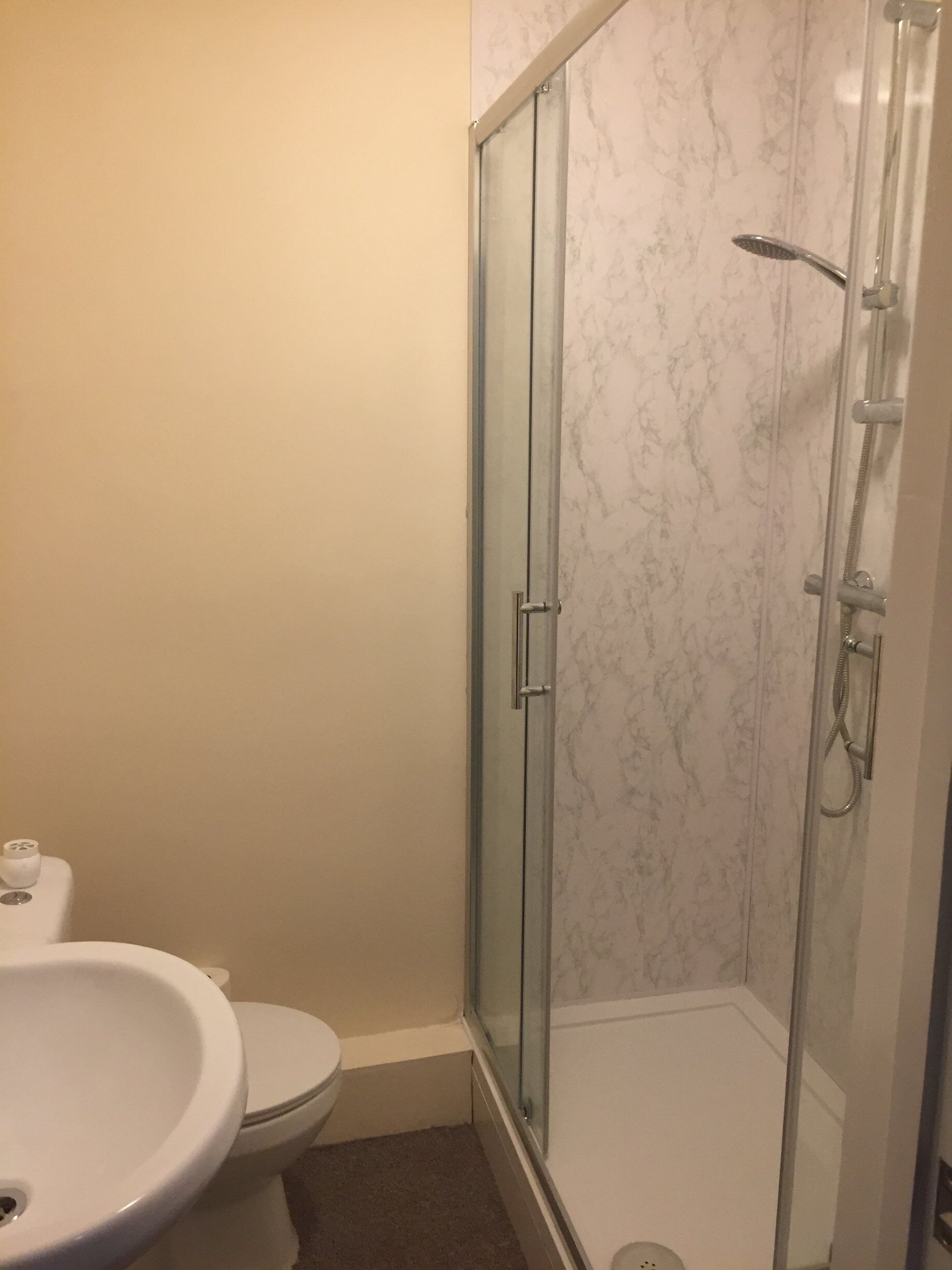 A bathroom with a glass-enclosed shower, a toilet, and a sink.