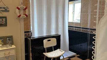 A bathroom with a black and white checkered floor, a white chair, a shower curtain, and a life preserver sign.