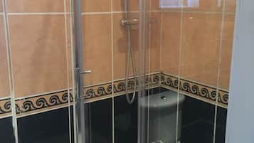 Et badeværelse med bruseniche, toilet og håndvask.