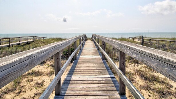 Une promenade en bois qui mène à la plage et offre une vue dégagée sur l’océan.