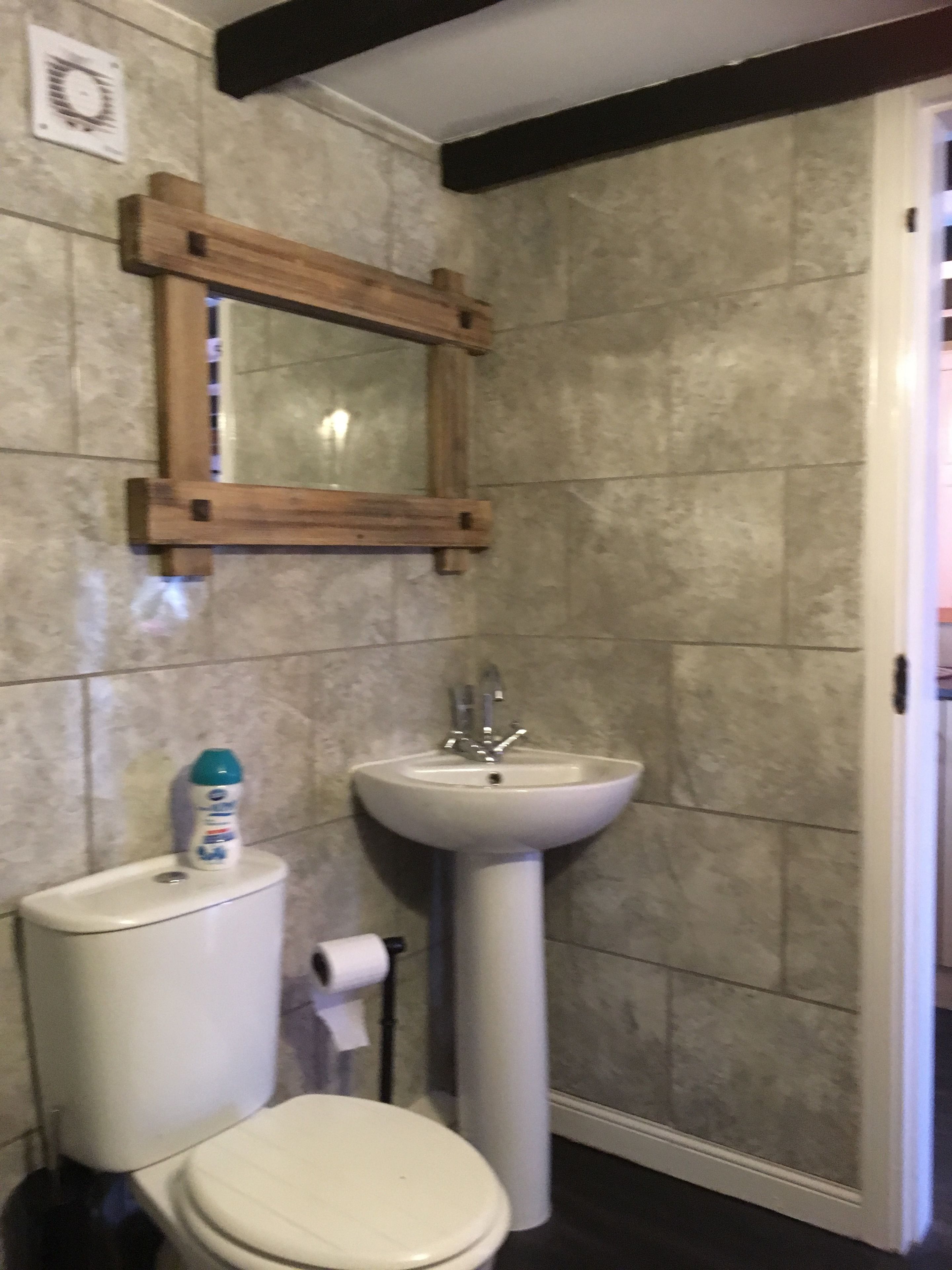 A bathroom with a toilet, sink, and mirror.
