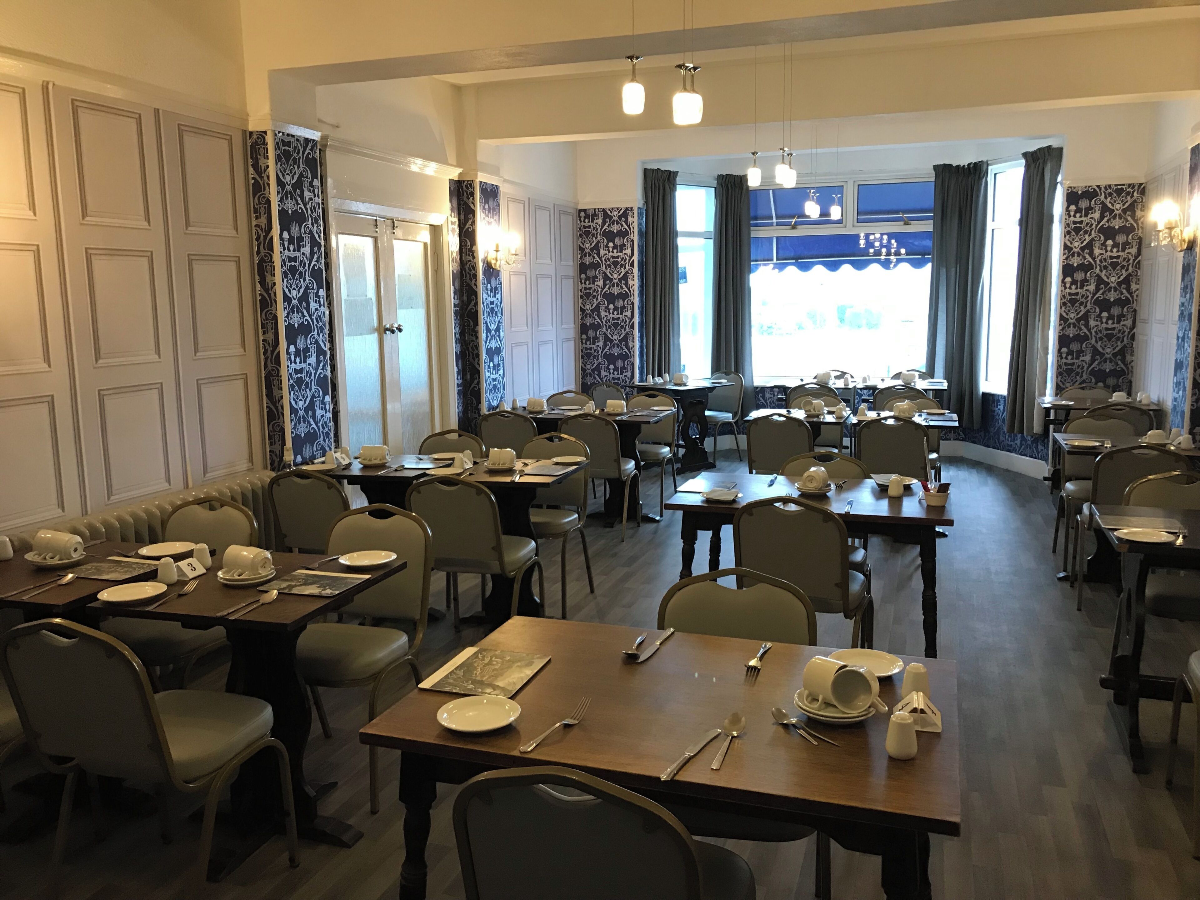 A dining area with multiple tables and chairs, some with table settings.