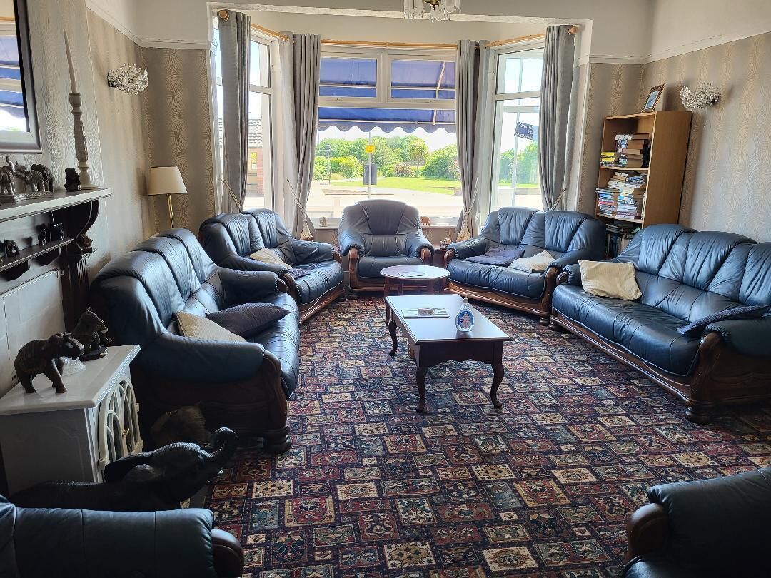 Una habitación con sofás de cuero, una mesa de centro, una estantería y una alfombra estampada.