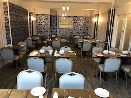 A restaurant with multiple tables and chairs, a patterned wall, and a chandelier.