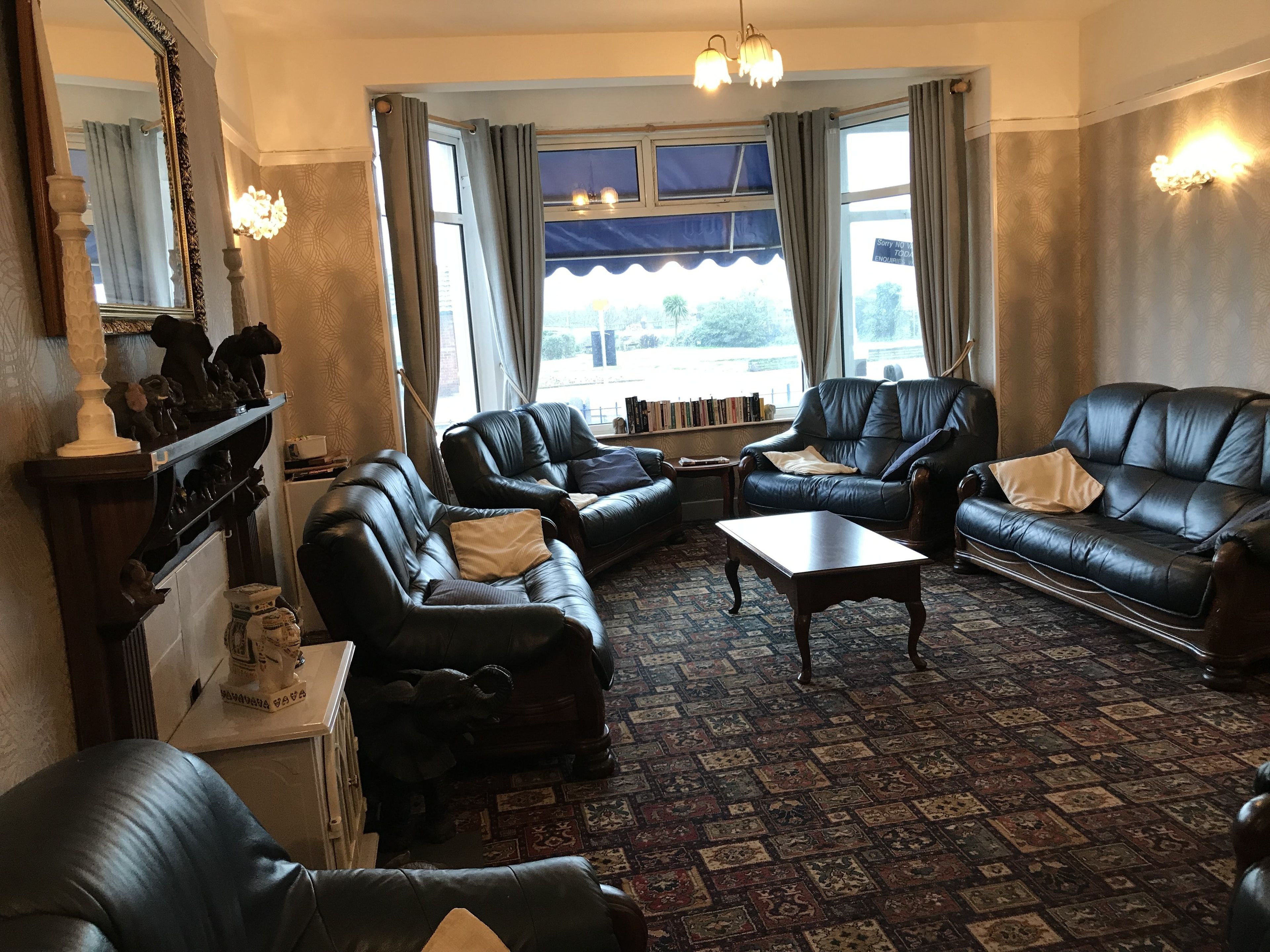 A traditional living room with leather sofas, a coffee table, and a patterned carpet.
