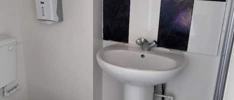 Een badkamer met toilet, wastafel en spiegel.