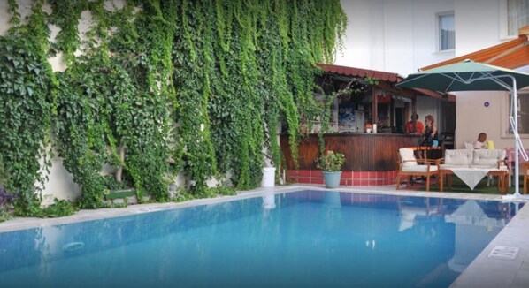 Alberca al aire libre, sombrillas en la alberca y camastros