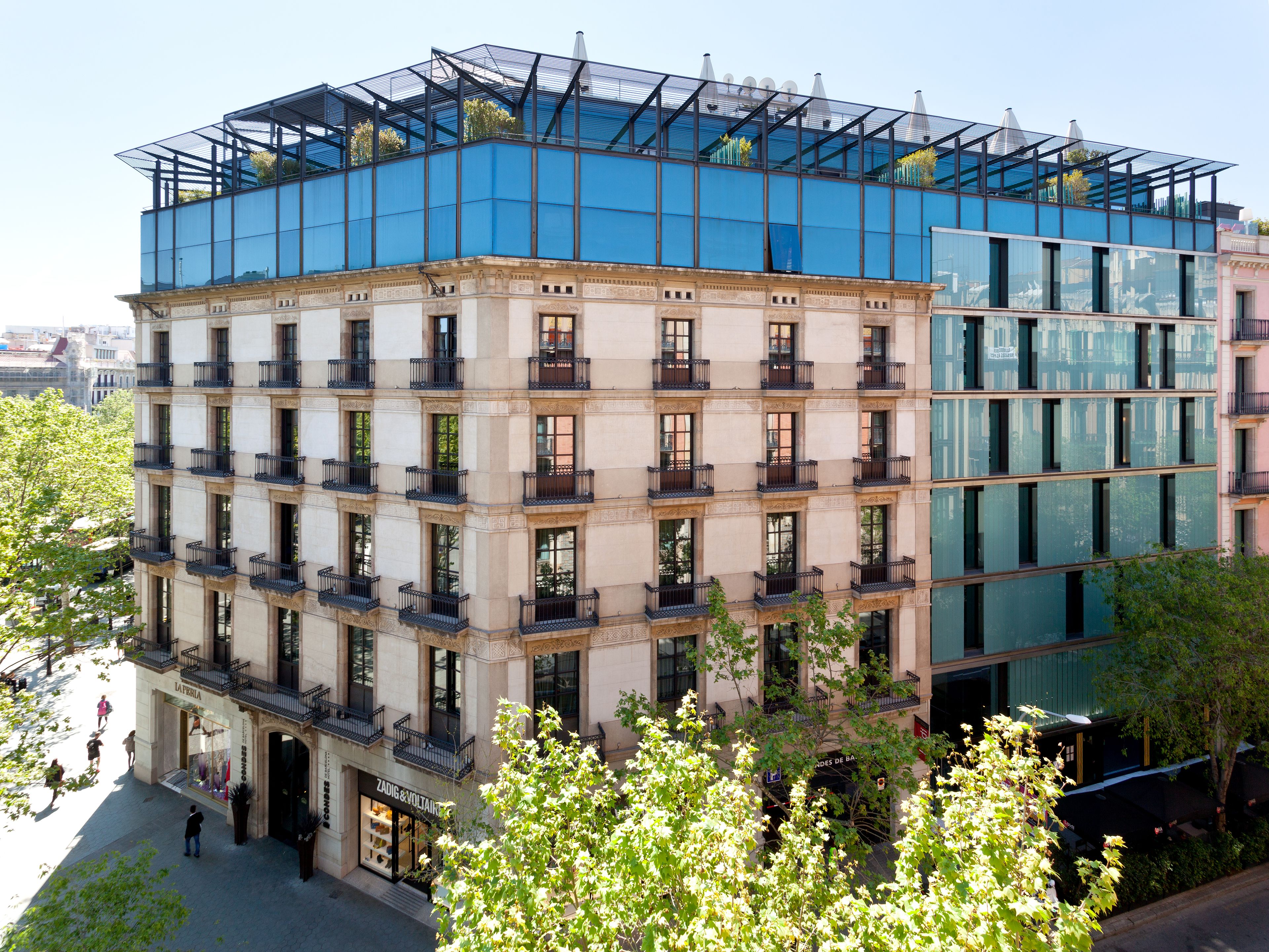Ein mehrstöckiges Gebäude mit einer Mischung aus klassischer und moderner Architektur, mit Balkonen und großen Fenstern.