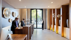 A modern reception area with a desk, a computer, and a person standing by the entrance.