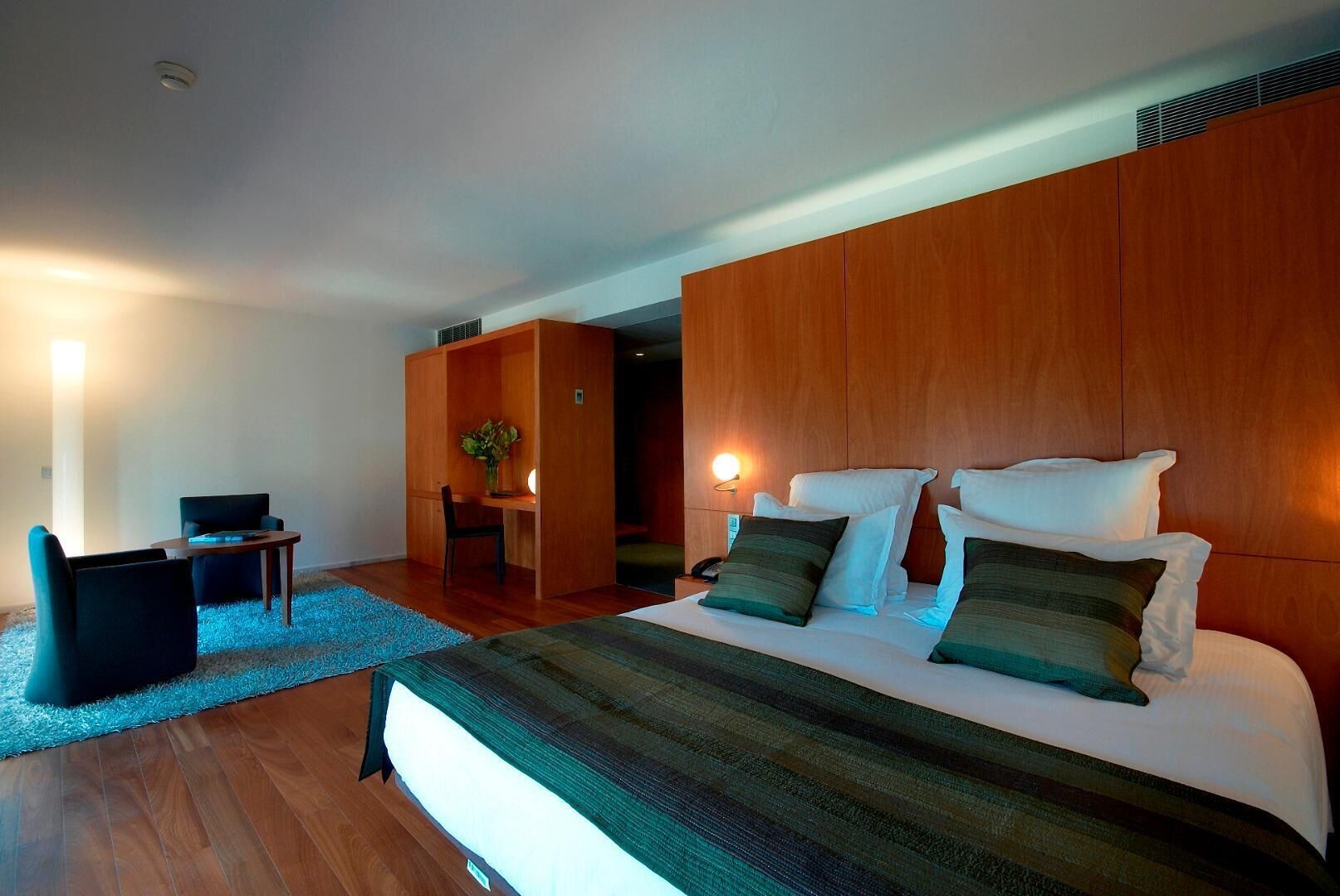 A modern hotel room with a large bed, a desk, and a chair.