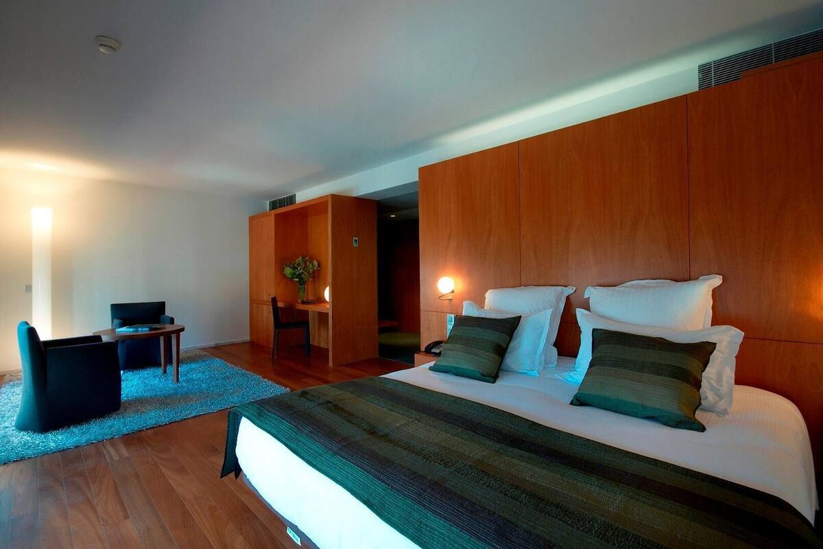 A modern hotel room with a large bed, a desk, and a chair.