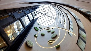 A modern interior with a curved ceiling, glass railings, and circular seating areas.