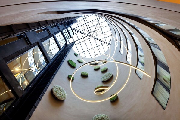 Un intérieur moderne avec un plafond incurvé, des rampes en verre et des espaces de détente circulaires.