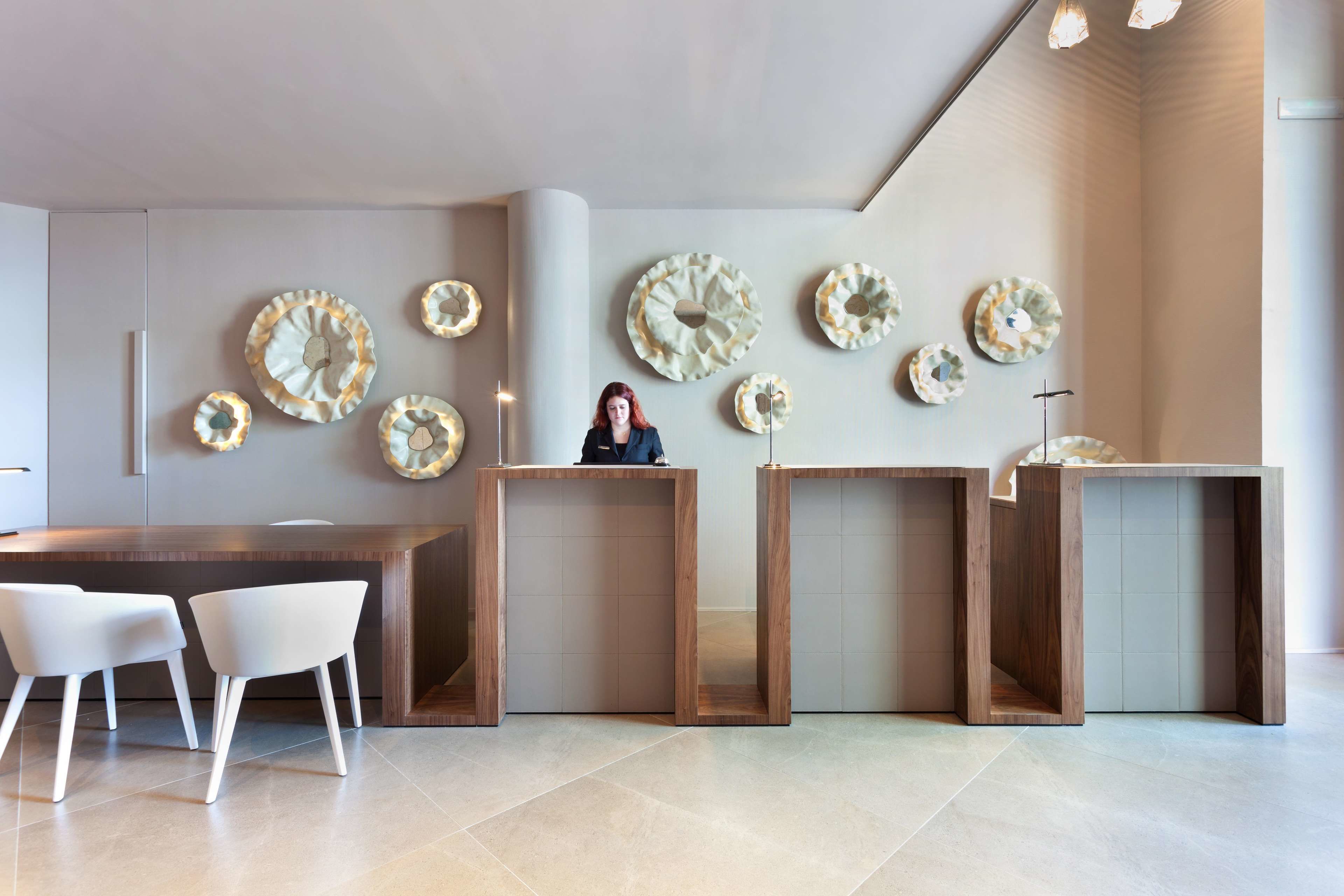 A modern interior with a wooden reception desk, white chairs, and decorative wall plates.