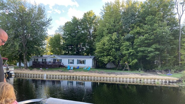 Une maison au bord d’un lac paisible, avec un quai et une balançoire.