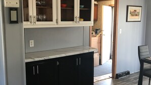 Une cuisine avec des meubles de couleur sombre, un plan de travail en marbre et une vue sur la salle à manger adjacente.