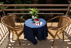 A round table with a blue tablecloth, two wicker chairs, a potted plant, and a bowl of strawberries. - Hotel Cormoran (Riccione)